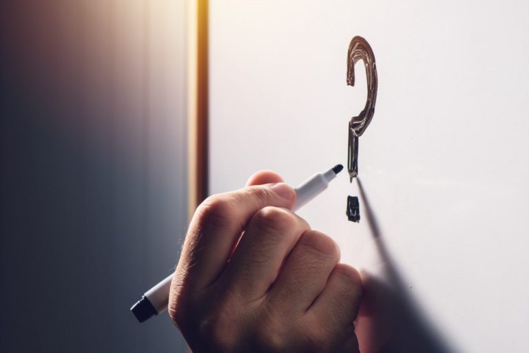 FAQ 1 Confused businessman writing question mark on whiteboard